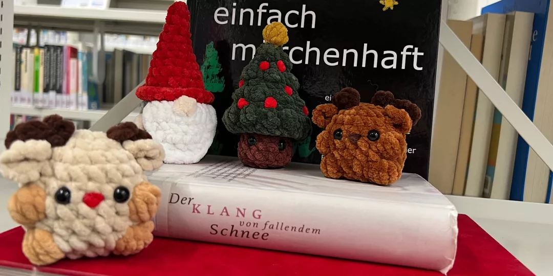 vier gehäkelte Figuren/Tiere vor Bücher