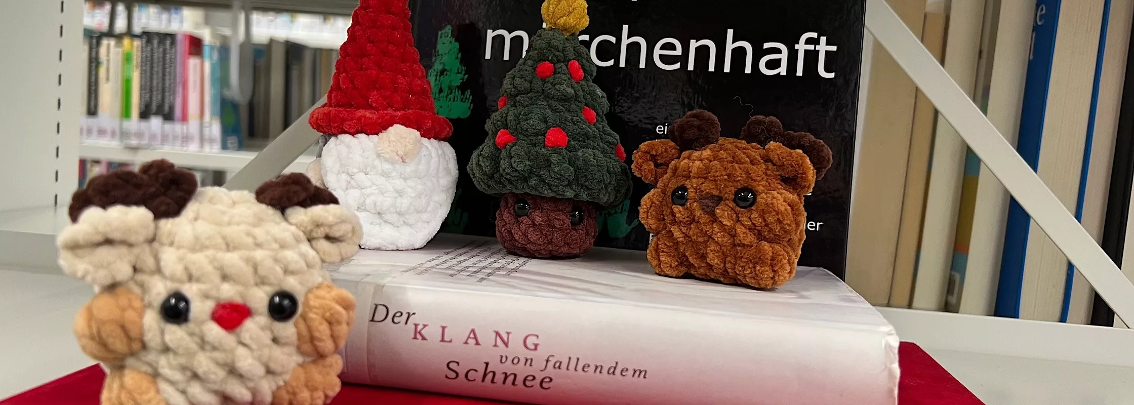 vier gehäkelte Figuren/Tiere vor Bücher